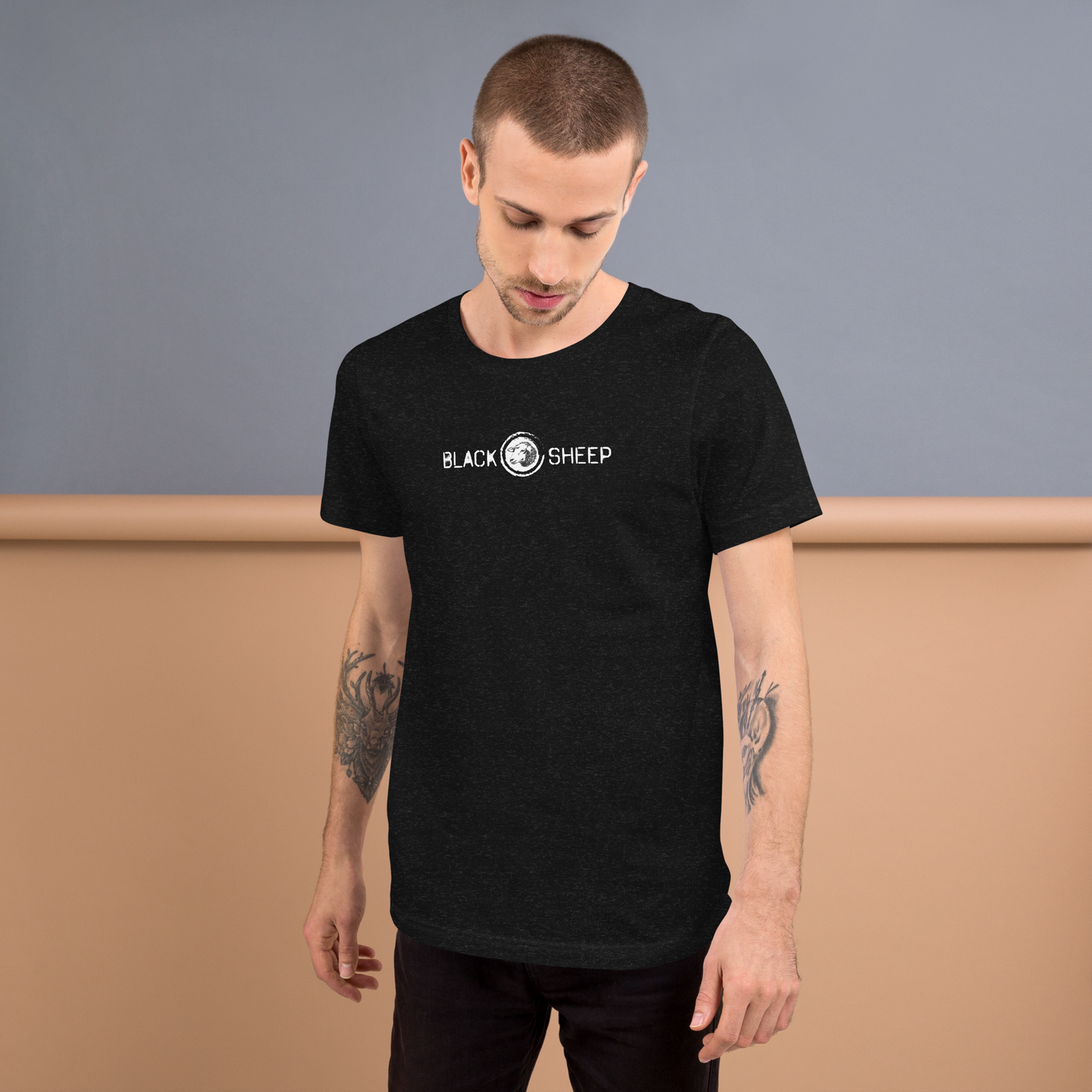 Mann trägt heather schwarzes Unisex T-Shirt mit Black Sheep Schriftzug und kleinem Schafskopf auf Brusthöhe