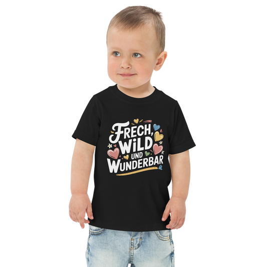 Ein Junge trägt ein schwarzes T-Shirt mit buntem "Frech, Wild und Wunderbar" Print mit Herzchen 
