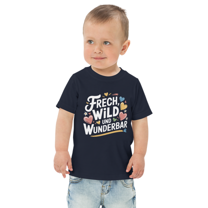 Ein Junge trägt ein navy T-Shirt mit buntem "Frech, Wild und Wunderbar" Print mit Herzchen 