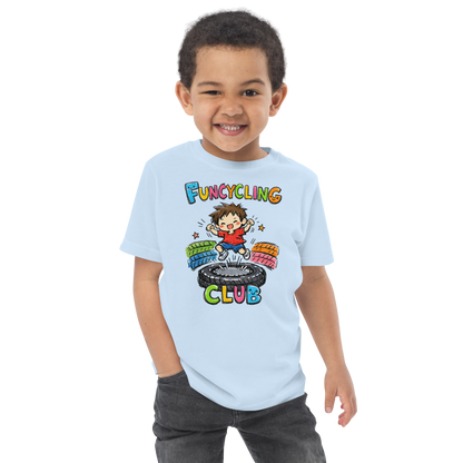 Ein Junge trägt ein hellblaues T-Shirt mit buntem "Funcycling Club" Print und einem Jungen der auf einem Reifen Trampolin springt