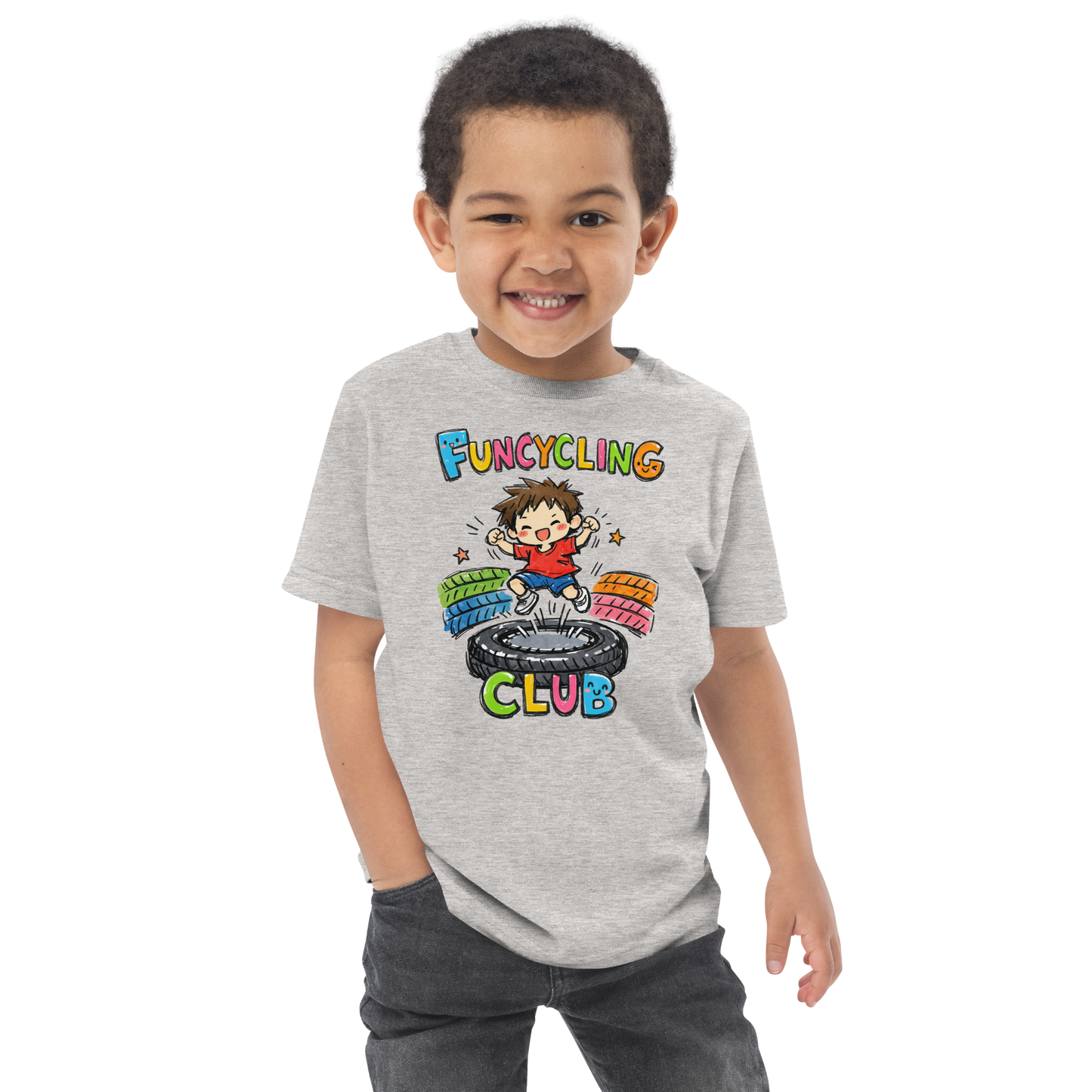 Ein Junge trägt ein graues T-Shirt mit buntem "Funcycling Club" Print und einem Jungen der auf einem Reifen Trampolin springt