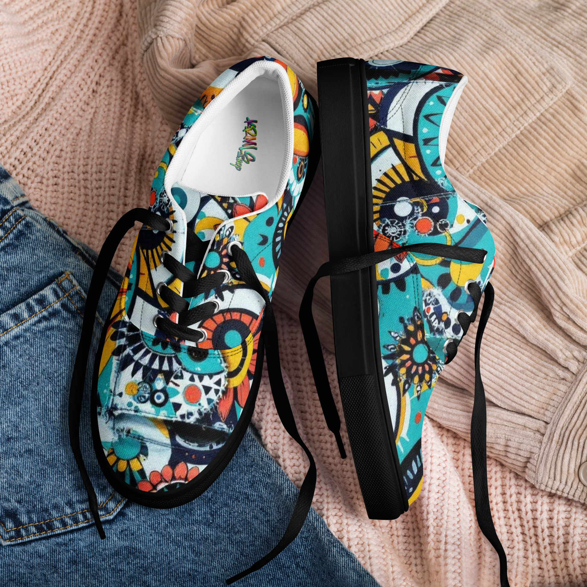 Bunte Sneaker mit abstraktem Muster im urbanem Stil und schwarzem Gummirand liegen auf Klamotten