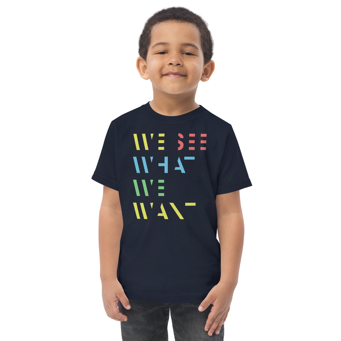 Junge trägt navy T-Shirt mit buntem We See What We Want Schriftzug